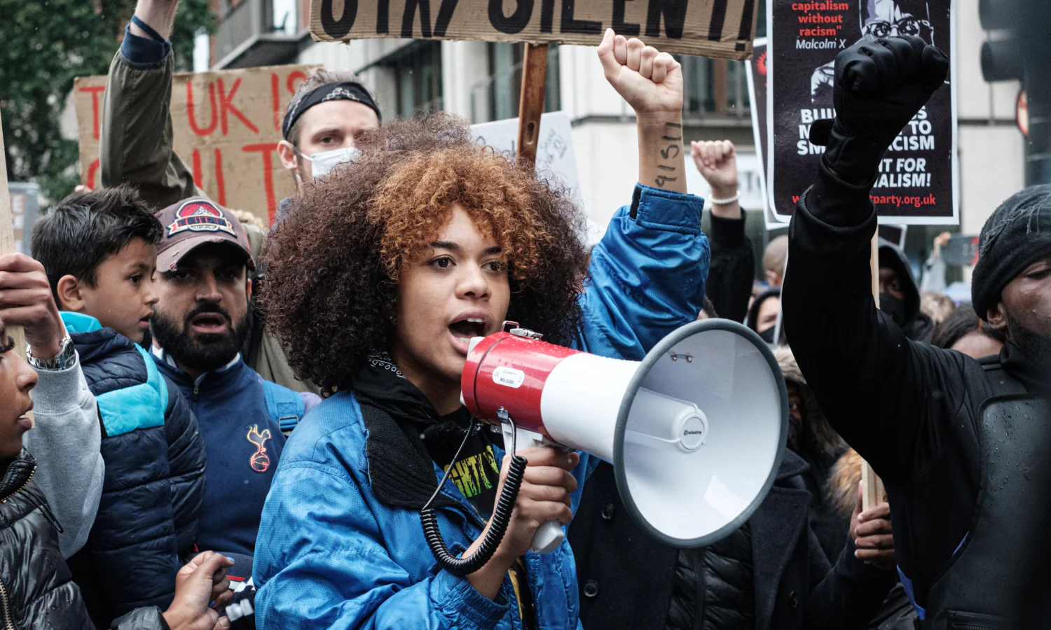 Bilden visar en person som håller en megafon, i en folkmassa, kanske en demonstration.