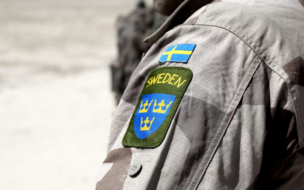 Ärmen på en uniform med ett påsytt märke som visar lilla riksvapnet, tre kronor, i blått och gult och en liten svensk flagga. Foto: iStock