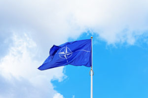 Natos flagga vajar mot en blå himmel med vita moln. Foto: iStock