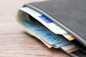 En bild på en gråbrun plånbok, där Euro-sedlar sticker upp.