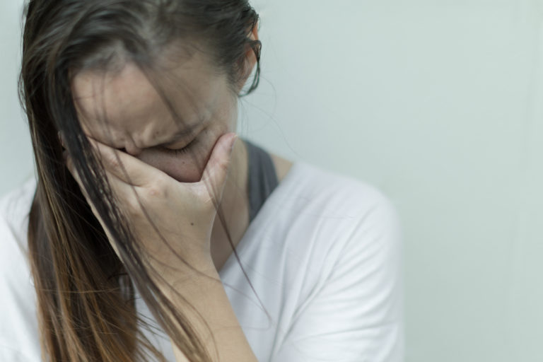Bild på en förtvivlad kvinna som håller ansiktet i en av sina händer. Foto: iStock