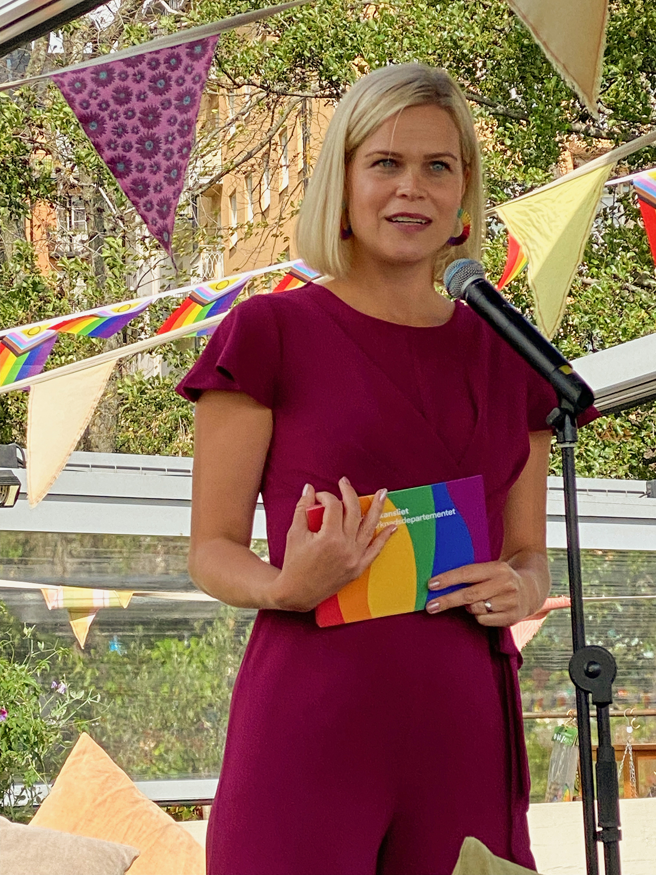 Jämställdhetsminister Paulina Brandberg i vinröd klänning talar på restaurang Mälarpaviljongen, Stockholm Pride 2023. Foto Ulf Schyldt