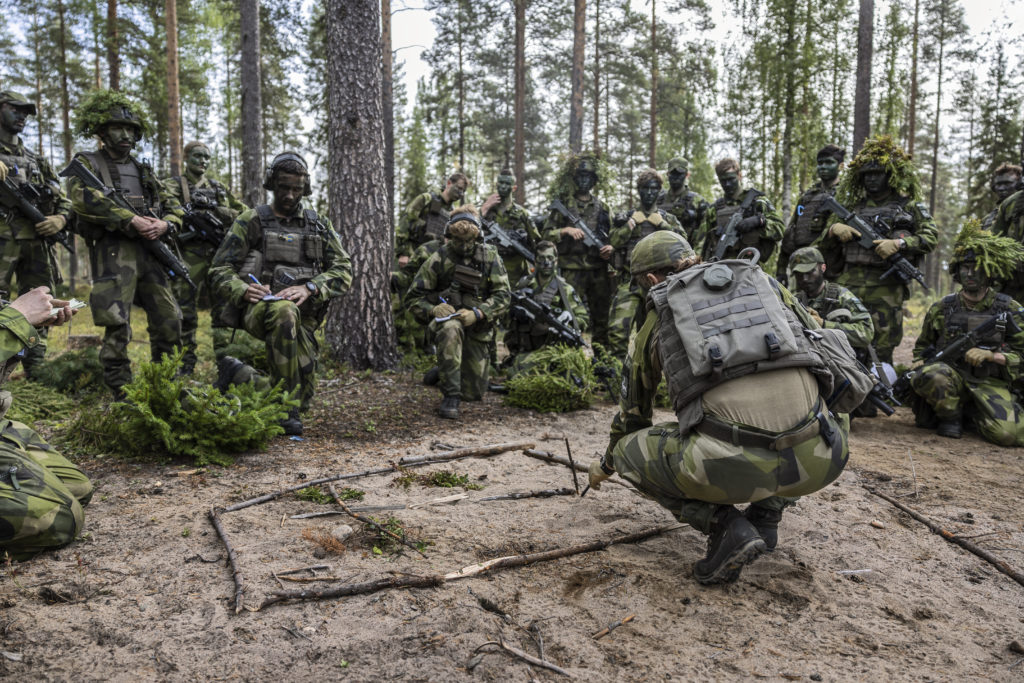Soldater under övning i skogen tar emot instruktioner och studerar en terrängskiss. Foto Försvarsmakten/Bezav Mahmood