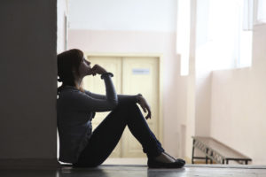 Bilden visar siluetten av en skolelev som sitter på golvet och funderar. Foto: iStock