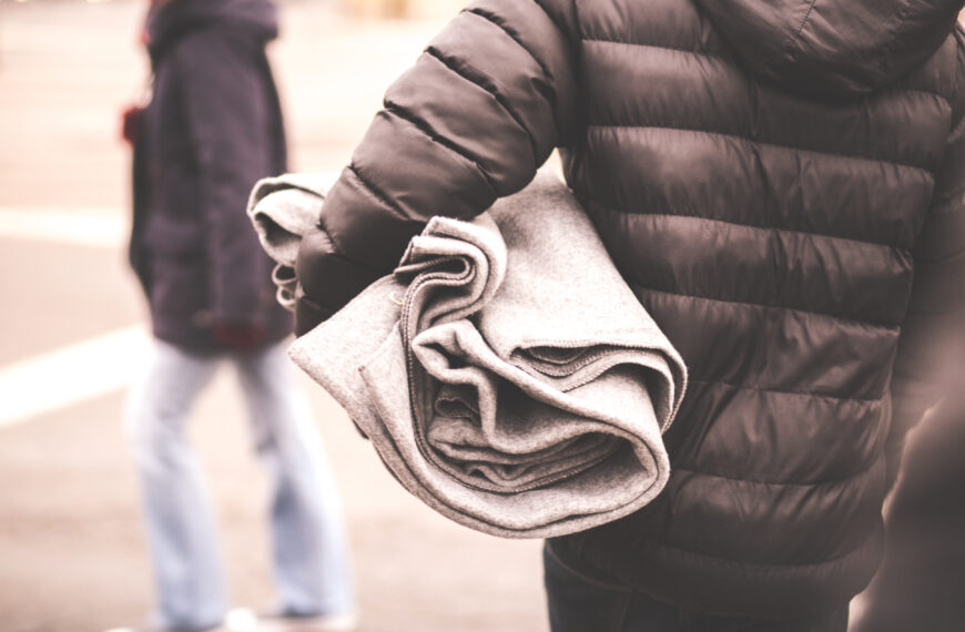 Bilden visar en person i täckjacka bakifrån, som bär en filt. Foto: iStock