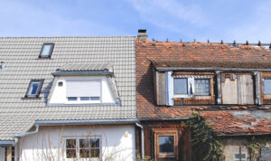Bilden visar två hus, alldeles intill. varandra. Det ena är vitt, med nytt tak och nyligen upprustat medan det andra ser slitet och förfallet ut. Foto: iStock