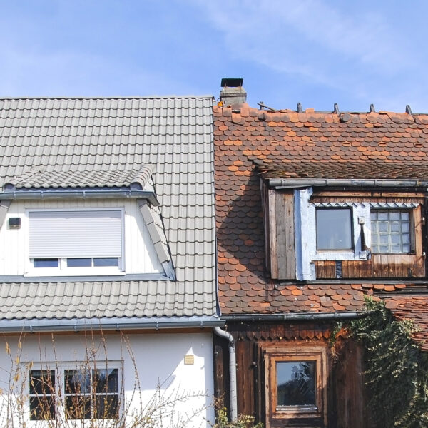 Bilden visar två hus, alldeles intill. varandra. Det ena är vitt, med nytt tak och nyligen upprustat medan det andra ser slitet och förfallet ut. Foto: iStock