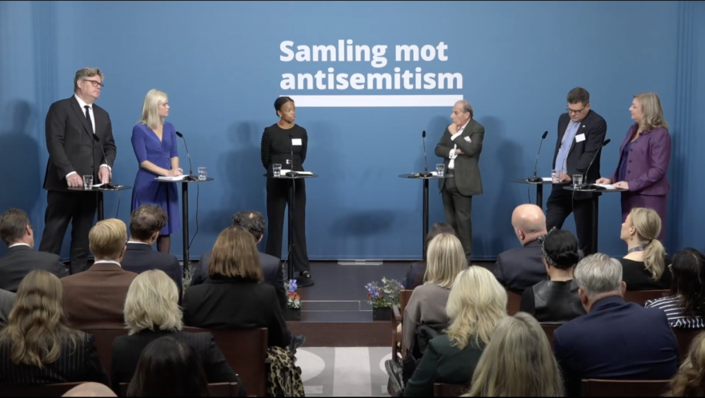 Den siata av fyra paneler som samtalade under symposiet Samling mot antisemitism. Från vänster: justitieminister Gunnar Strömmer (M), jämställdhetsminister Paulina Brandberg (L), Anna Urombi, generalsekreterare på Raoul Wallenberg Academy, Robert Weil, ordförande och grundare, Proventus AB, Jonas Trolle, chef för Center mot våldsbejakande extremism samt moderator Sofia Nerbrand