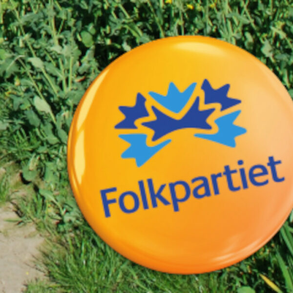 Bilden visar en oragne knapp som det står Folkpartiet på, mot en bakgrund av slingrande gröna växter